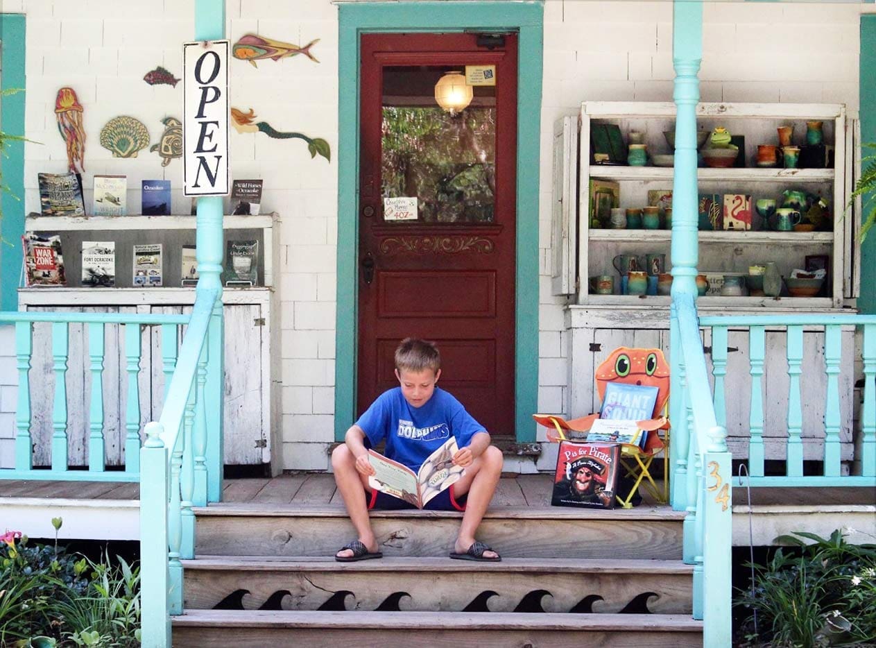 boy reading book on bookstore steps